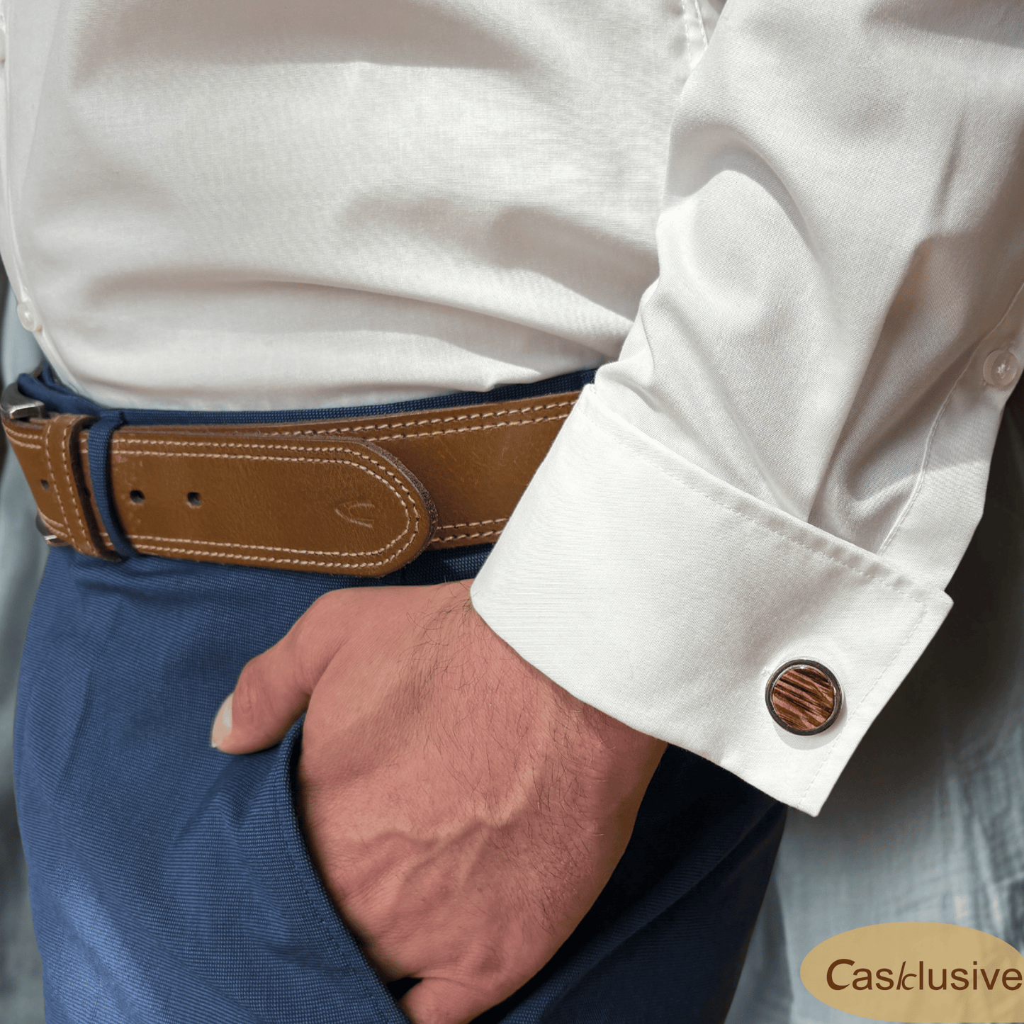 Ein Manschettenknopf an einem Hemd von einem Mann in einer blauen Anzughose. Nur die Koörpermitte