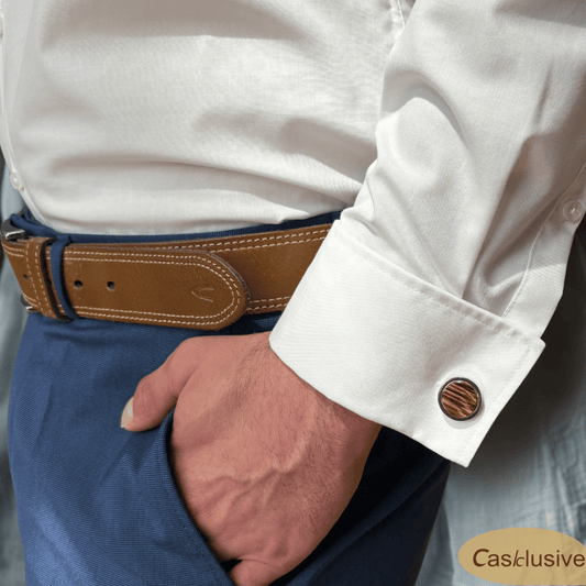 Ein Manschettenknopf an einem Hemd von einem Mann in einer blauen Anzughose. Nur die Koörpermitte