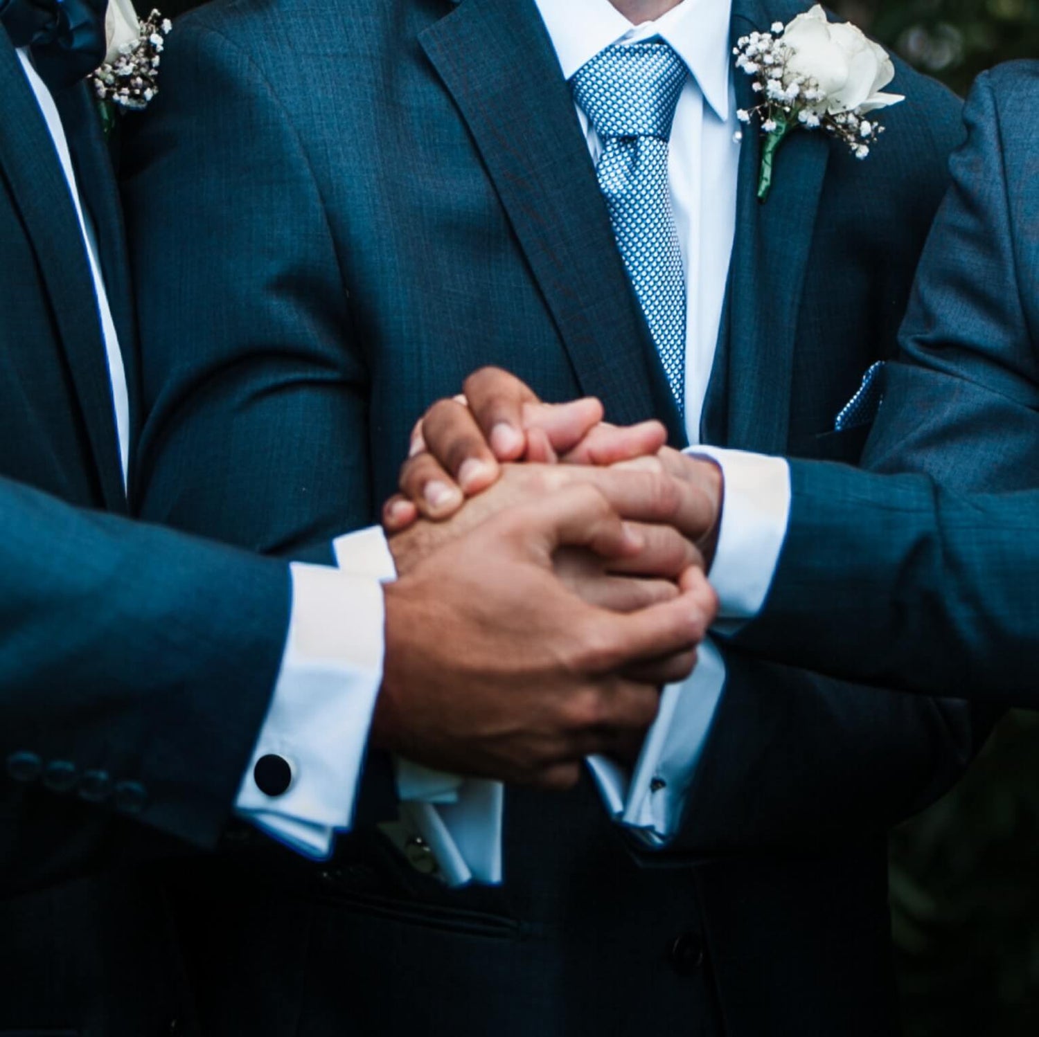 Bräutigam und Trauzeugen halten die Hände zusammen - am Hemd Manschettenknöpfe aus Whisky Fassholz