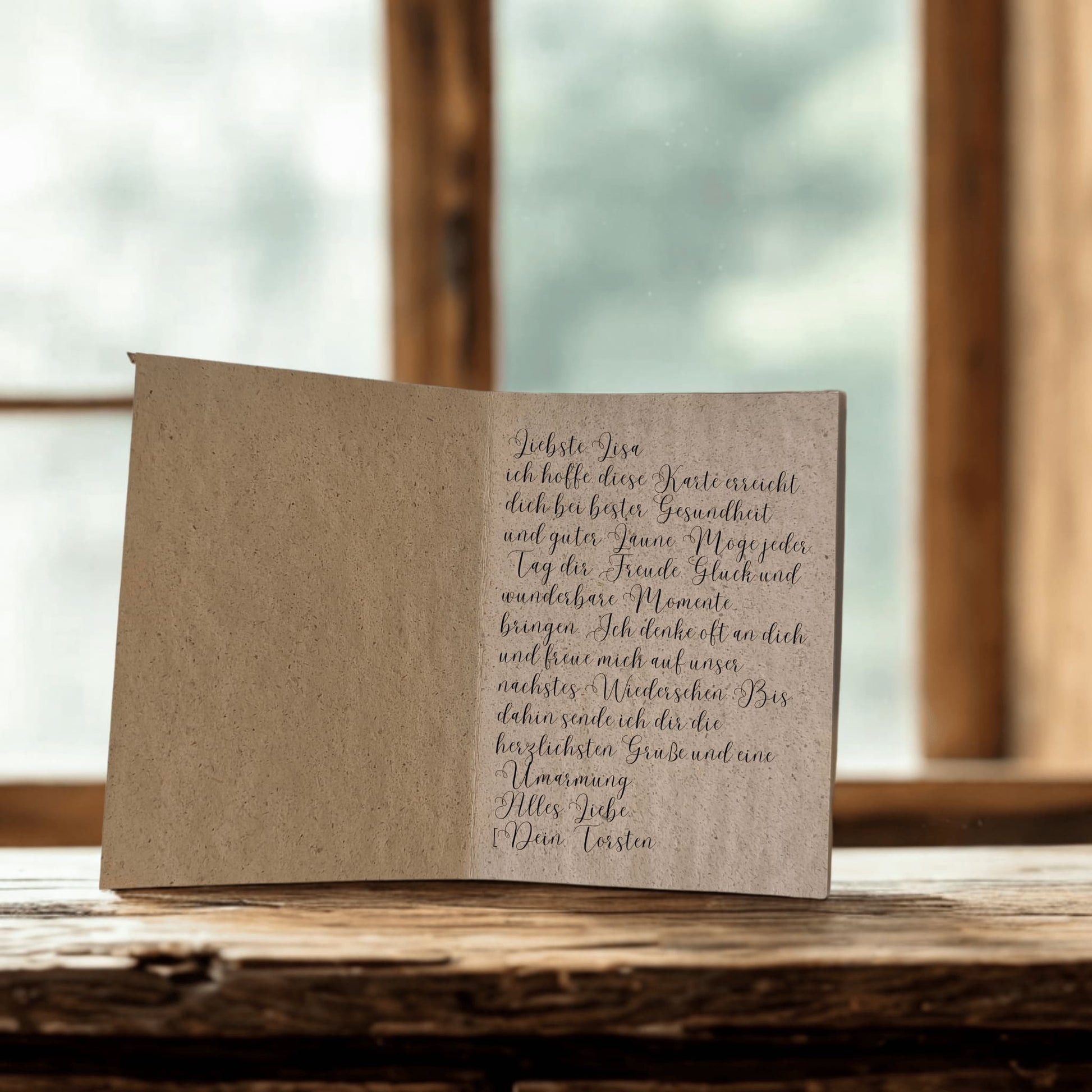 Die aufgeklappte handgeschöpfte Karte. Die rechte Seite ist mit einem Grußwort beschrieben